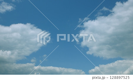 On a bright, cheerful day, there is a serene blue sky adorned with fluffy white clouds 128897525