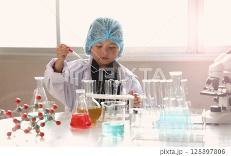 Kid and science. Child dress scientist learning conducts experiment in lab with colorful chemicals test tubes and molecular models. Inspiring early STEM education science learning and curiosity in kid 128897806