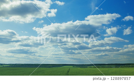 A beautiful, picturesque view of scenic skies and lush green fields under bright clouds A beautiful, picturesque view of scenic skies and lush green fields under bright clouds 128897857