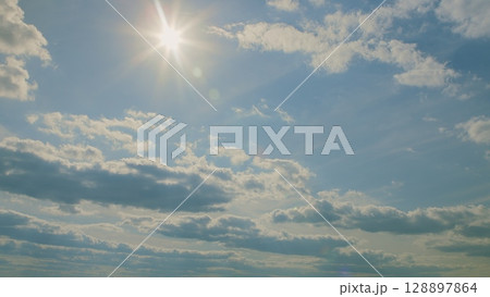 A beautiful sunny sky adorned with fluffy clouds and bright, radiant sunlight shining down A beautiful sunny sky adorned with fluffy clouds and bright, radiant sunlight shining down 128897864