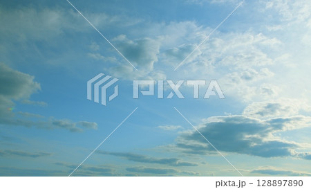 A beautiful composition of a tranquil blue sky adorned with fluffy white clouds 128897890