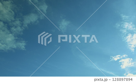 A Crystal Clear Blue Sky Adorned with Soft, Fluffy Clouds Captured on a Gorgeous Sunny Day 128897894