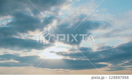 A stunningly beautiful sunset unfolds over a cloudy sky, adorned with brilliant rays of light 128897898