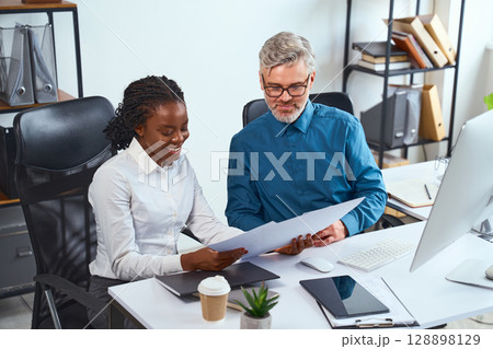 Teamwork Meeting Between Colleagues Discussing Documents in a Modern Office Environment Teamwork Meeting Between Colleagues Discussing Documents in a Modern Office Environment 128898129
