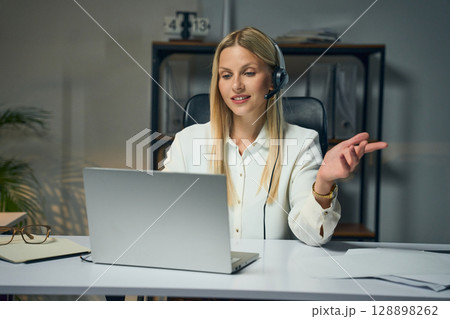 Professional Businesswoman Conducting Online Meeting With Headset and Laptop in Office 128898262