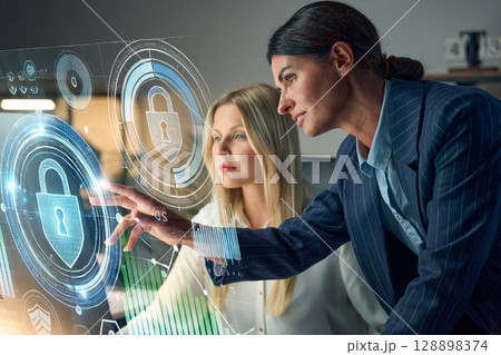 Two Professionals Working on Cybersecurity Solutions With Holographic Interface Screens Two Professionals Working on Cybersecurity Solutions With Holographic Interface Screens 128898374