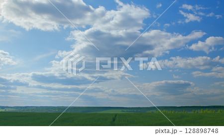 A Serene and Picturesque Landscape Featuring an Expansive Blue Sky with Fluffy White Clouds A Serene and Picturesque Landscape Featuring an Expansive Blue Sky with Fluffy White Clouds 128898748
