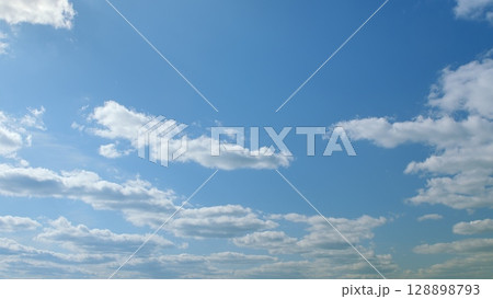 A Beautiful and Clear Blue Sky that is Adorned with Fluffy White Clouds on a Sunny Day 128898793