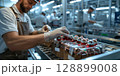 Factory worker preparing christmas baubles for shipment on assembly line 128899008