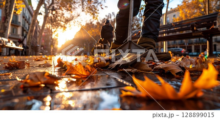 Street cleaner sweeping autumn leaves at sunrise in a city 128899015