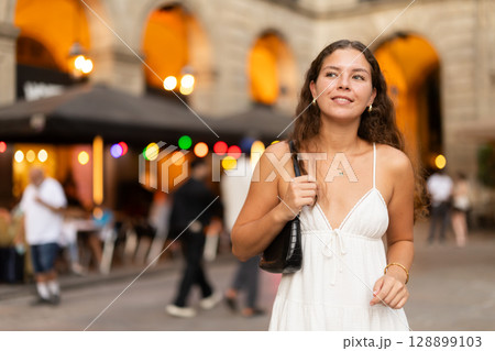 young woman walks through the evening streets of Barcelona 128899103