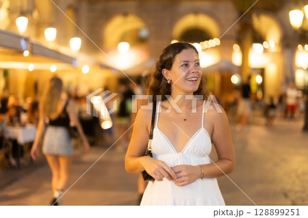young woman walks along an evening street in Barcelona young woman walks along an evening street in Barcelona 128899251