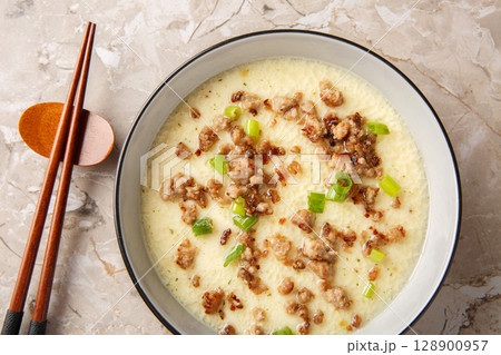 Tender steamed eggs with crispy fried pork and green onions close-up in a bowl. Horizontal top view 128900957