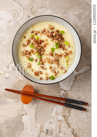 Steamed Eggs with Crispy Pork and green onion closeup in the bowl. Vertical top view Steamed Eggs with Crispy Pork and green onion closeup in the bowl. Vertical top view 128900959