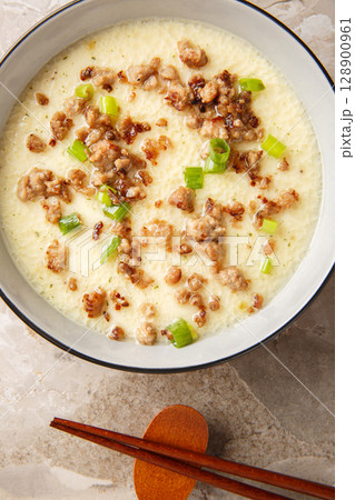 Asian Steamed Eggs with fried Pork mince and green onion closeup in the bowl. Vertical top view Asian Steamed Eggs with fried Pork mince and green onion closeup in the bowl. Vertical top view 128900961