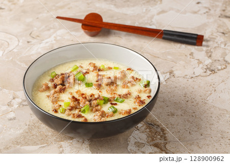 Tender steamed eggs with crispy fried pork and green onions close-up in a bowl. Horizontal 128900962