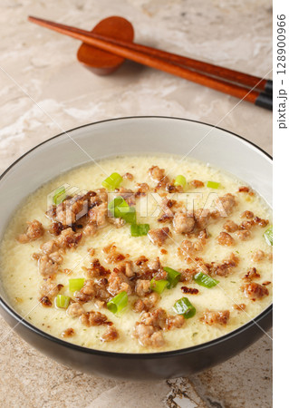 Steamed Eggs with Crispy Pork and green onion closeup in the bowl. Vertical Steamed Eggs with Crispy Pork and green onion closeup in the bowl. Vertical 128900966
