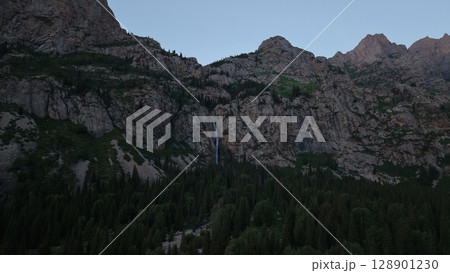 Waterfall cascading down rocky mountainside at twilight in the wilderness 128901230