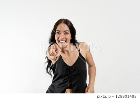 Young latin woman pointing and laughing on white background 128901488