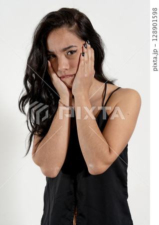 Young latin woman holding face showing sadness and worry Young latin woman holding face showing sadness and worry 128901598