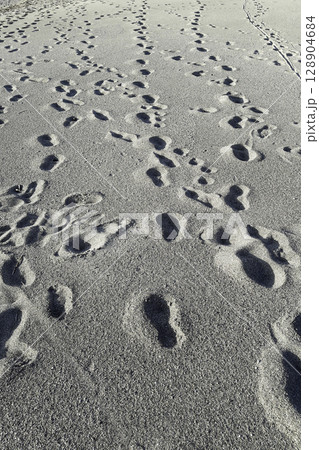 Many footsteps on a sandy beach 128904684