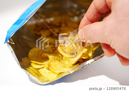 rotten potato chips in hand. potato chips with spices in a packet.  128905478