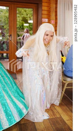 Young female animator in princess costume dancing in front of children. 128905482