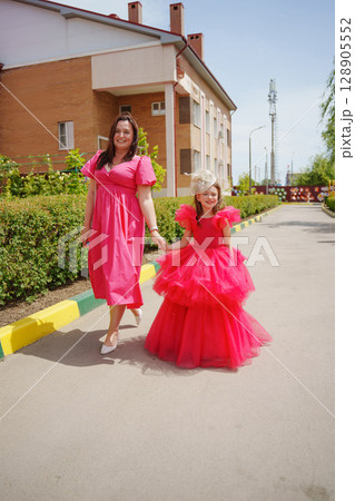 Happy well-dressed family on a walk. Mom and little daughter/ 128905552