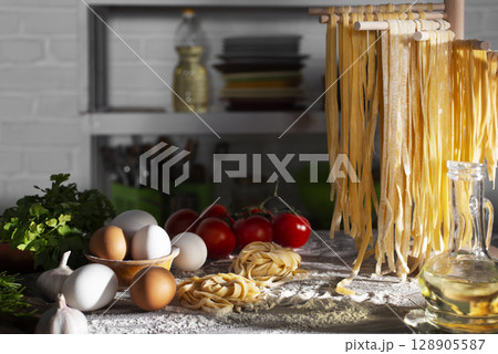 Homemade noodles hanging on wooden dryer rack over messy kitchen table background low angle front view Homemade noodles hanging on wooden dryer rack over messy kitchen table background low angle front view 128905587
