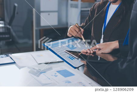 Focused young businessman signing agreement with skilled lawyer in eyeglasses. Concentrated financial advisor showing place for signature on paper contract document to male client at meeting in office Focused young businessman signing agreement with skilled lawyer in eyeglasses. Concentrated financial advisor showing place for signature on paper contract document to male client at meeting in office 128906209