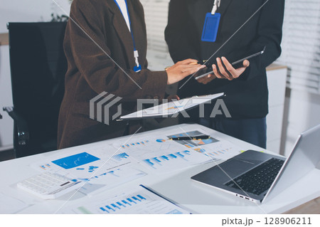 Focused young businessman signing agreement with skilled lawyer in eyeglasses. Concentrated financial advisor showing place for signature on paper contract document to male client at meeting in office 128906211