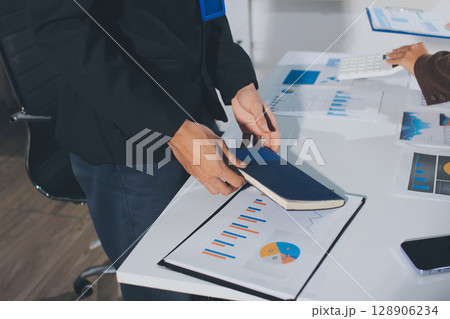 Focused young businessman signing agreement with skilled lawyer in eyeglasses. Concentrated financial advisor showing place for signature on paper contract document to male client at meeting in office 128906234