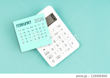 February 2026 calendar card with calculator on blue color background. 128906900