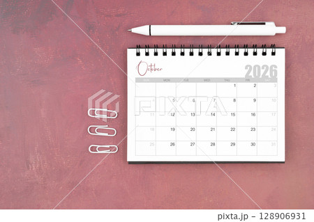 Desk calendar for October 2026 and pen with paper clips on red table, Flat lay. Desk calendar for October 2026 and pen with paper clips on red table, Flat lay. 128906931