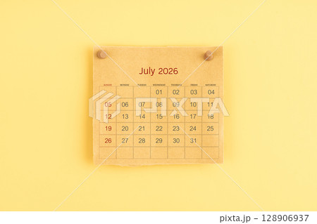 July 2026 brown calendar with wooden thumbtack on yellow color background. 128906937