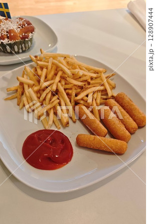 Plate with crispy french fries, breaded cheese sticks and a serving of ketchup on a white table Plate with crispy french fries, breaded cheese sticks and a serving of ketchup on a white table 128907444
