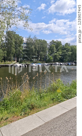 Sunny canal scene with moored boats, lush greenery and a clear blue sky in a peaceful urban area Sunny canal scene with moored boats, lush greenery and a clear blue sky in a peaceful urban area 128907445
