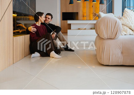 Cozy moment between a couple in a modern living room during the evening Cozy moment between a couple in a modern living room during the evening 128907878