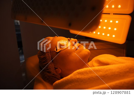 Woman undergoing light therapy treatment at a spa in a tranquil setting 128907881