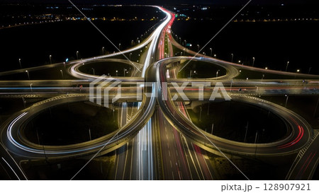 Aerial view of multi-level highway interchange glowing at night with organized traffic flow and symmetrical design. Generative AI. Aerial view of multi-level highway interchange glowing at night with organized traffic flow and symmetrical design. Generative AI. 128907921