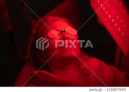 Woman relaxing with light therapy treatment in a wellness center Woman relaxing with light therapy treatment in a wellness center 128907934