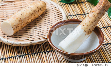 すり鉢に入った長芋と皮付きの長芋を竹ざるにのせた和の食材構成 128908019