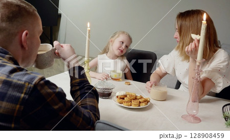 Loving family sharing morning meal, enjoying waffles and tea, warm candlelight illuminating breakfast nook with intimate, relaxed connection Loving family sharing morning meal, enjoying waffles and tea, warm candlelight illuminating breakfast nook with intimate, relaxed connection 128908459