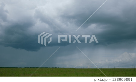 A Dramatic Cloudy Sky Looms Over Vibrant Green Fields, Creating a Stunning Visual Contrast 128909891
