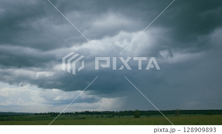 A dramatic sky looms over a beautiful green landscape, capturing natures unique mood 128909893