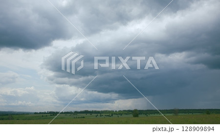 The Dramatic Cloudy Skies That Sweep Over the Expansive Green Landscape Below Them 128909894