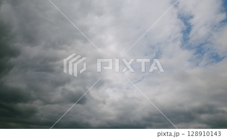 A beautifully dynamic overcast sky with patches of bright blue peeking through the clouds 128910143
