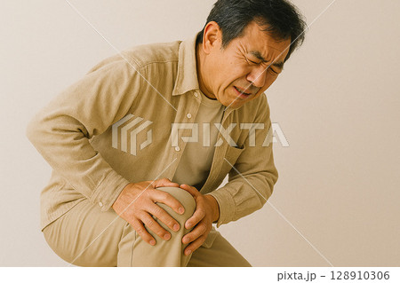 膝を押さえて苦しむ中年男性 128910306