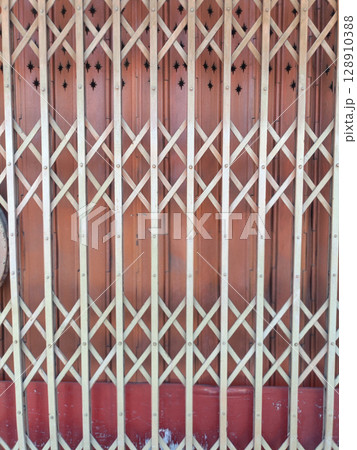 Wooden gate with lattice design and star shaped cutouts at top, set against reddish brown background, creating decorative and functional barrier Wooden gate with lattice design and star shaped cutouts at top, set against reddish brown background, creating decorative and functional barrier 128910388