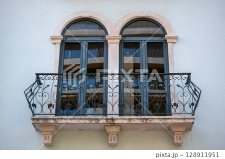 Elegant Balcony with Arched Windows and Ornate Ironwork Elegant Balcony with Arched Windows and Ornate Ironwork 128911951